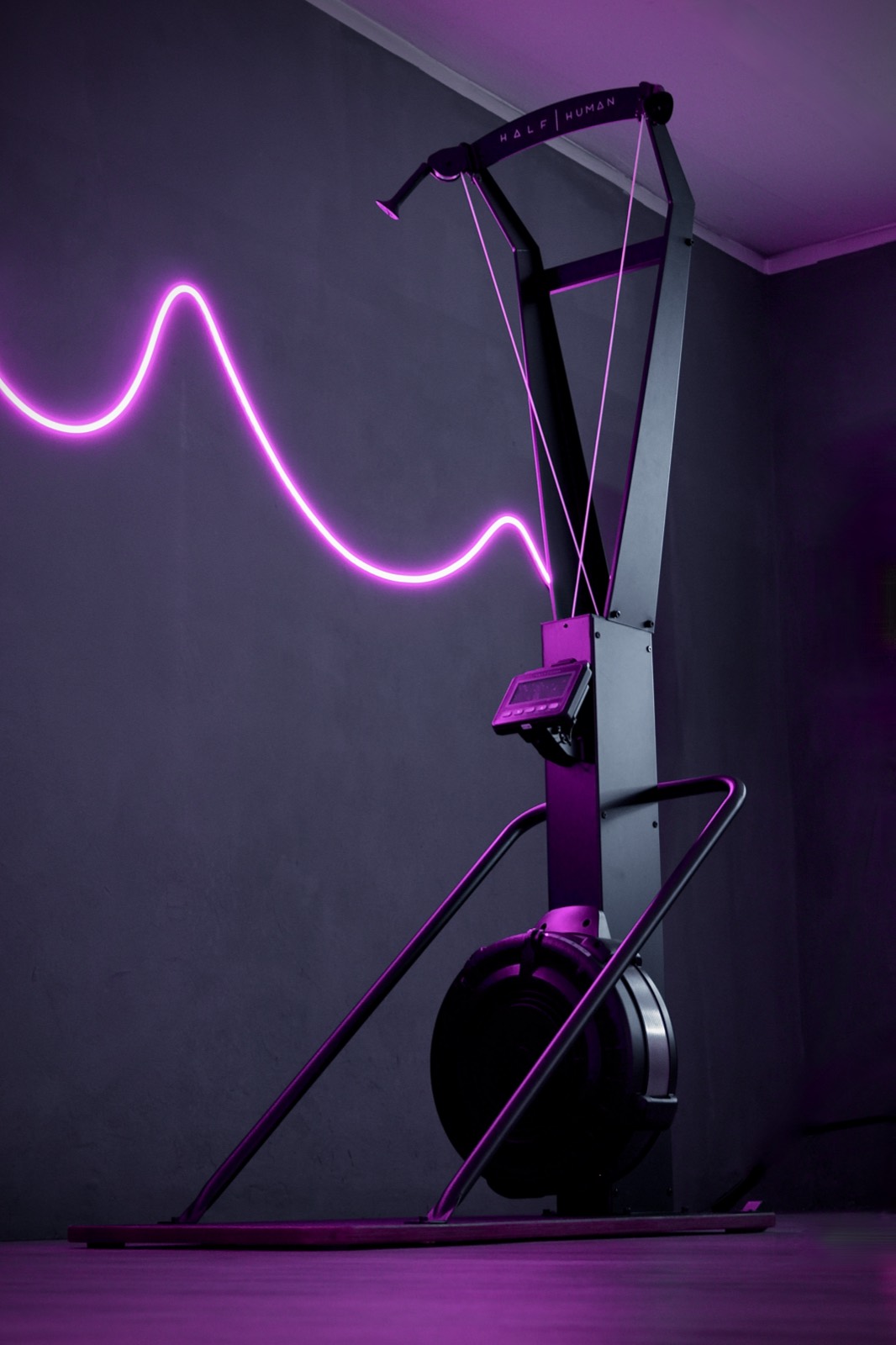 Ein SkiErg an der Wand mit der pinken Neonwelle